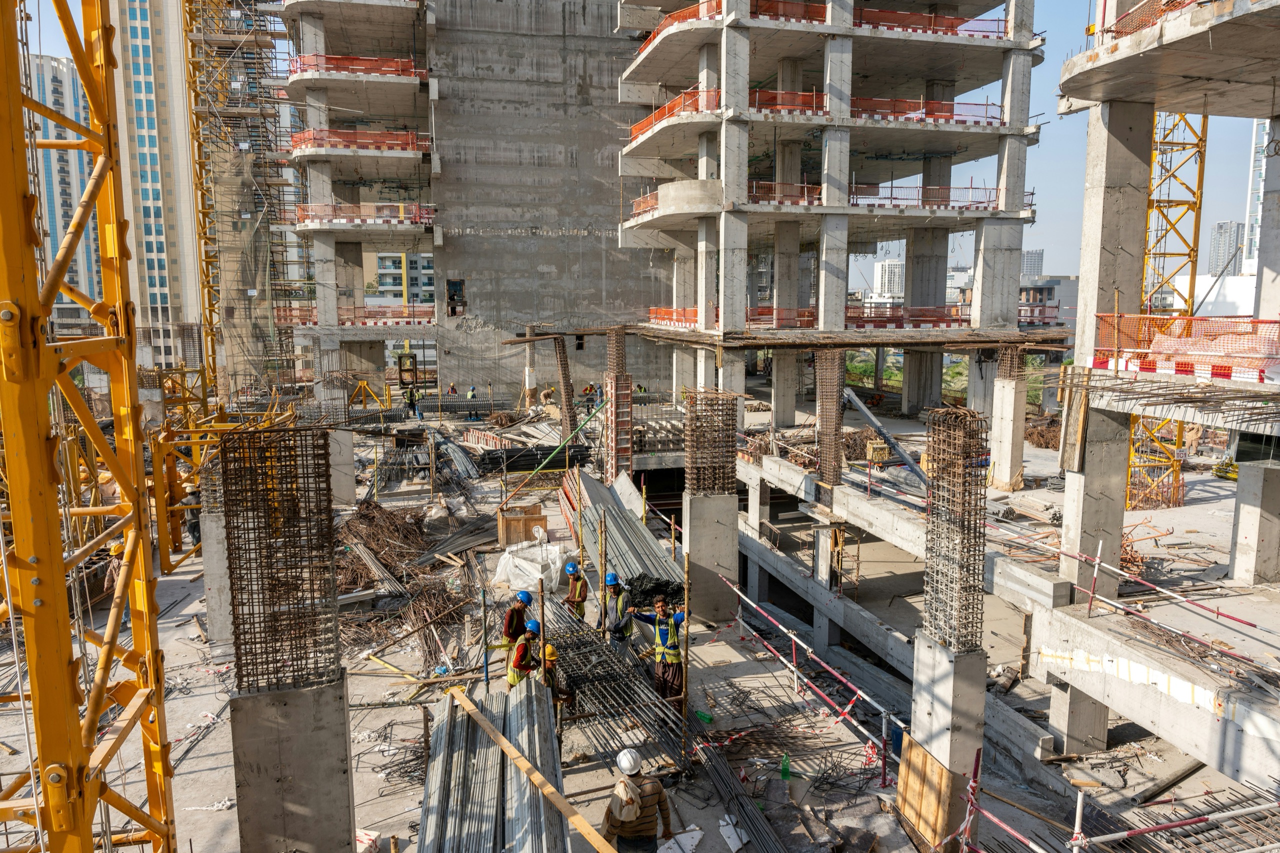 A high-rise concrete frame under construction with cranes in Jumeirah Village Circle
